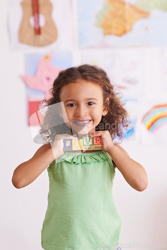 Image of Girl, smile and learn with blocks in portrait, child development and growth with letters. Female person, kid and abc or alphabet for language, kindergarten and creative game for education at school