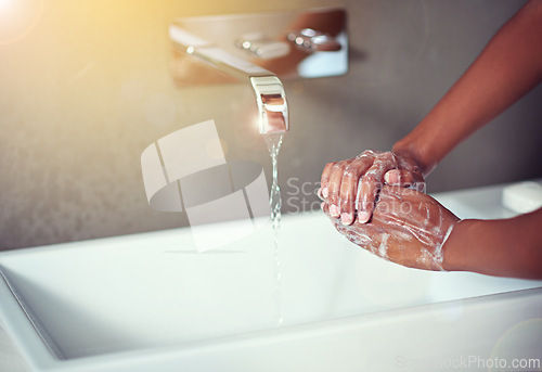 Image of Washing hands, bathroom and person with water in home with soap for hygiene, bacteria or germs in morning. Faucet, sink or basin with foam, liquid or splash for cleaning, virus or wellness in house