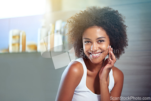 Image of African woman, portrait and facial cream with smile, wellness or afro in home bathroom for morning routine. Girl, person and serum with cosmetics, beauty and transformation with skincare in apartment