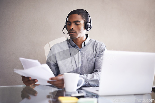 Image of Businessman, laptop and headphones with paperwork for call center, online advice or consulting at office. Black man, consultant or African employee with documents and computer for customer service