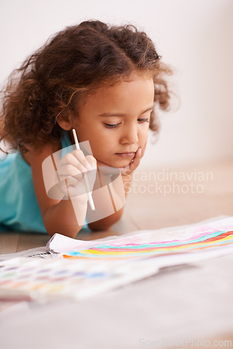 Image of Young girl, painting and brush on floor with paper, creativity and drawing for learning or childhood. Toddler, motor skills and growth for development child enjoying, hobby or playing at home