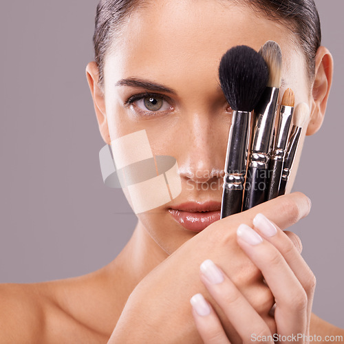 Image of Woman, beauty and brush with makeup, portrait and studio for glamour and radiance and lip gloss. Female person, blush cosmetics and foundation in grey background, tools and attractive confidence