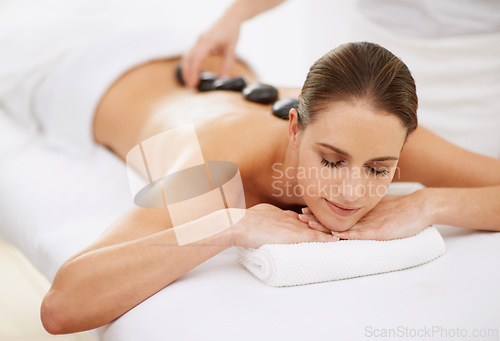 Image of Relax, hot stone massage and girl at spa for health, wellness and luxury holistic treatment. Self care, zen and woman in natural body therapy, comfort and calm pamper service at hotel with therapist