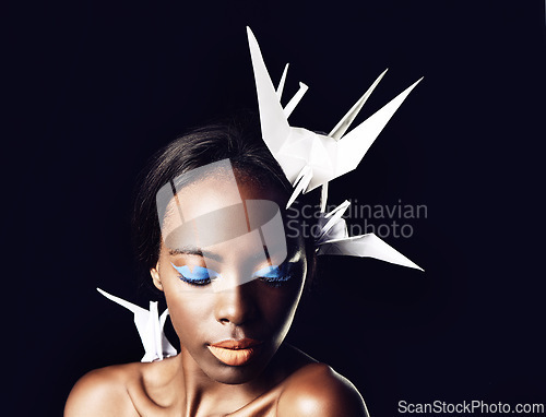 Image of Black woman, makeup and fine art with cosmetics, origami birds or dove on a dark studio background. Closeup or face of African female person or model with beauty or blue eye shadow on mockup space