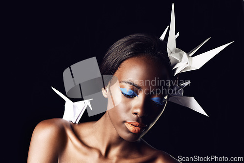 Image of Black woman, makeup and fine art with beauty, cosmetics or origami birds on a dark studio background. Closeup or face of African female person or model with dove or blue eye shadow on mockup space