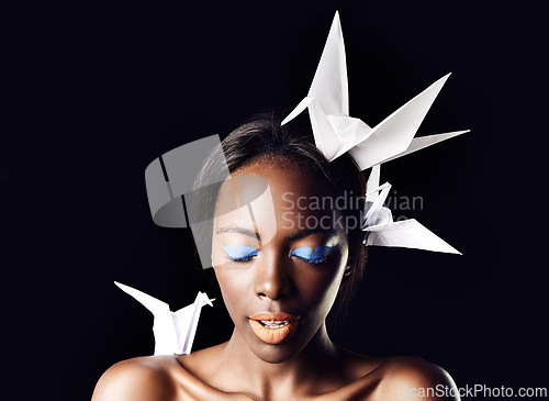 Image of Black woman, eyeshadow and fine art with beauty, dove or origami birds on a dark studio background. Closeup or face of African female person or model with blue makeup or cosmetics on mockup space