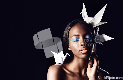 Image of Black woman, makeup and fine art with beauty, origami birds or cosmetics on a dark studio background. Closeup or face of African female person or model with dove or blue eye shadow on mockup space