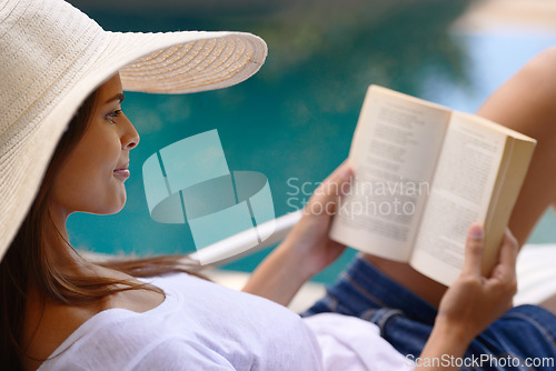 Image of Vacation, relax and woman at pool with book, hat and lounge with happy summer travel on hotel patio. Holiday, deck chair and girl with smile, reading and story with sunshine, weekend or luxury resort