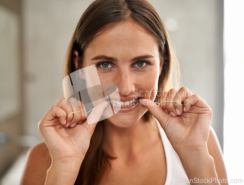 Image of Bathroom, portrait and woman flossing teeth for dental health, care and hygiene for smile. House, female person and cleaning tooth with thread, grooming and oral routine on morning for girl in home