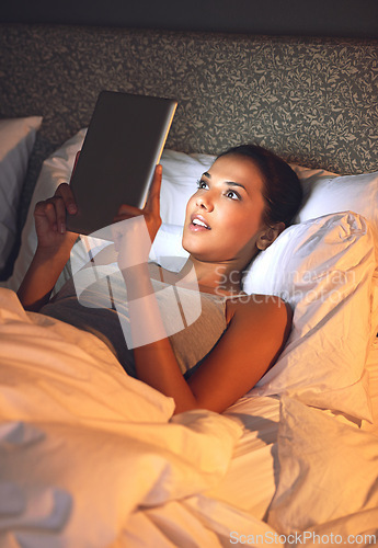 Image of Night, tablet and ebook for woman with smile in bed, relax and rest on soft mattress in bedroom. Digital, technology and reading for entertainment of female person, girl and adult in apartment