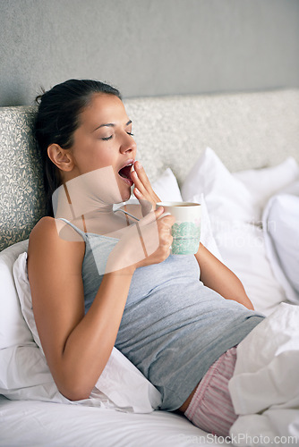 Image of Woman, relax and tea in morning with yawn for waking up, tired and exhausted in home. Female person, bed and sleepy gesture with coffee mug in apartment for weekend, day off and beverage on pillow