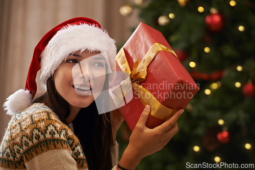 Image of Christmas, happy and woman with present at her home for festive celebration, event or party. Smile, guess and young female person with gift box for xmas surprise in living room at modern apartment.