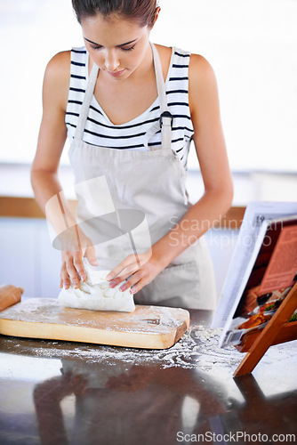 Image of Female person, wheat or dough in kitchen to bake bread with apron and flour on counter. Woman, bakery and cookbook for recipe or ingredients, roller and board to make pastry at home or house
