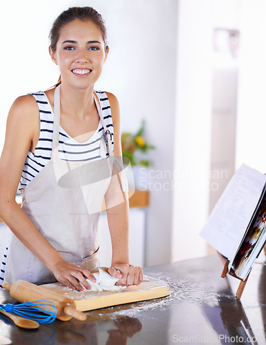 Image of Portrait, woman and dough in kitchen to bake bread with apron and flour on counter. Female person, bakery and cookbook for recipe or ingredients, smiling and happy to make pastry at home or house