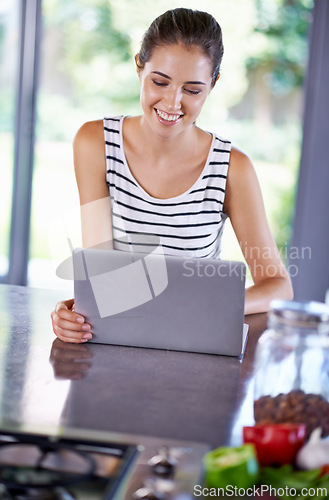 Image of Woman, happy and laptop on kitchen counter, female person and home on internet. Google it, browsing cooking recipes and social media, online search with technology for organic and healthy food ideas