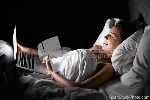Image of Bedroom, laptop and night with woman streaming content, video or browsing social media in dark home. Bed, computer and subscription with young person in apartment to relax on weekend time off