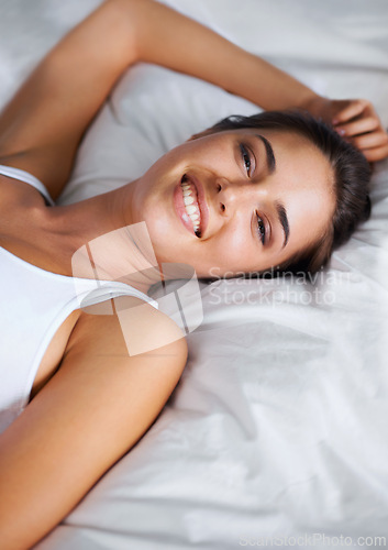 Image of Portrait, relax and smile from woman on bed of apartment, comfortable and rest on soft mattress. House, morning and female person wake up from dream on pillow with happiness for break on weekend