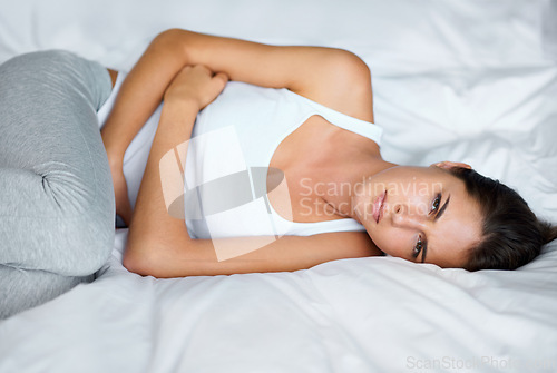 Image of Woman, stomach ache and pain in bed with digestion issue, menstruation cramps or endometriosis. Gut health crisis, colon blockage or constipation with bloating from stress, PMS or gastro at home