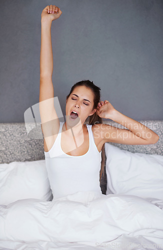Image of Woman, stretching and wake up in bed with yawn in morning with fatigue after resting. Tired, girl and sitting in bedroom on calm holiday or exhausted on vacation in hotel or home with burnout