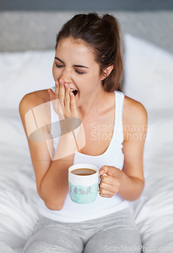 Image of Woman, fatigue and yawning with tea in bed, waking up from sleeping or nap with morning routine at home. Insomnia, tired and sleepy in bedroom, warm drink or beverage for breakfast and start day