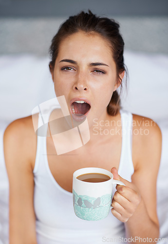 Image of Woman, tired and yawning with tea in bed, waking up from sleeping or nap with morning routine at home. Insomnia, fatigue and sleepy in bedroom, warm drink or beverage for breakfast and start day