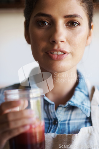 Image of Woman, glass and juice with kitchen, portrait and person with smoothie for health and wellness. Chef, drink and beverage for nutrition, vitamins and vitality for juicing diet with apron at home