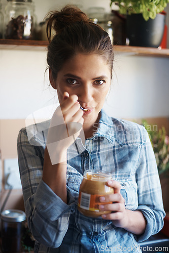 Image of Person, jar and peanut butter with kitchen, portrait and energy with spread for health and wellness. Woman, spoon and protein for nutrition, vitamins and vitality for diet at home or house to eat