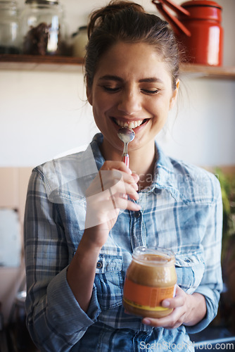 Image of Woman, jar and peanut butter with kitchen, smile and person for food for health and wellness. Nutritionist, spread and protein for nutrition, vitamins or vitality for diet at home or house with spoon