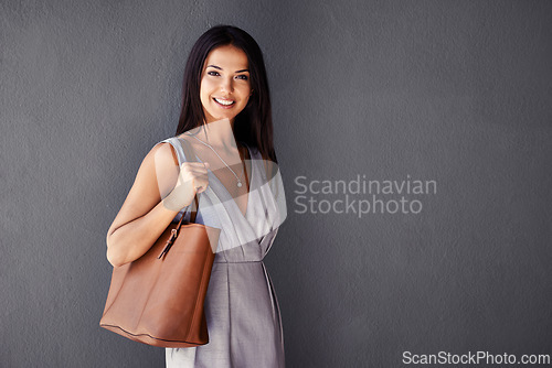 Image of Studio, portrait and handbag with woman, smile and accessories with dress and joy. Fashion, face and model with confidence, beauty and happiness with purse and style isolated on gray wall background