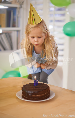 Image of Child, birthday and blow cake candle in home, celebration for three year old or party wish. Happy girl, dessert on table, excited or cheerful event for growth or special decoration and fun hat
