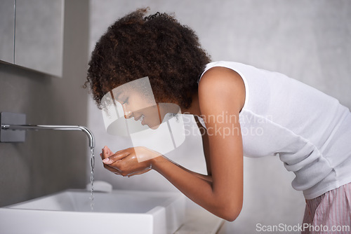 Image of African woman, bathroom and washing face with smile for hygiene, skincare and start morning routine. Girl, person and happy at basin with water for wellness, health and cleaning facial skin in home
