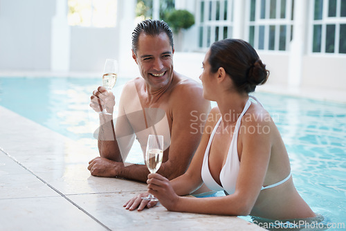 Image of Champagne, hotel and couple relax in pool for swimming, man and woman together with happiness for honeymoon. Resort, female person and guy smile for love in marriage, bonding and girl with bikini