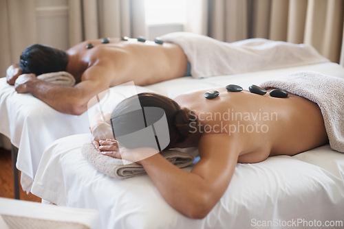 Image of Spa, relax and hot stone massage with couple on bed or table for luxury pamper treatment together. Beauty, wellness or detox with husband and wife at resort or salon for natural stress relief
