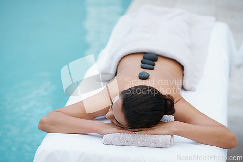 Image of Relax, hot stone massage and woman at pool at spa for health, zen wellness and luxury holistic treatment. Self care, peace and girl on table for body therapy, comfort and calm pamper service at hotel