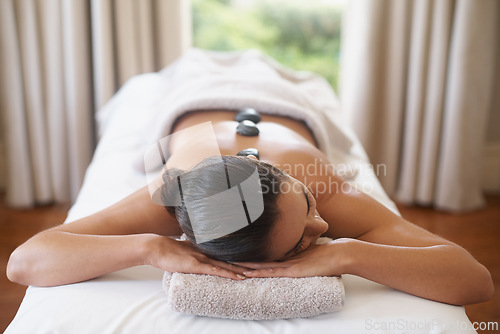 Image of Relax, rocks and woman at spa for massage, peace and calm for skincare at luxury resort. Beauty, therapy and person at salon with hot stone on back for body treatment, health or rest for wellness