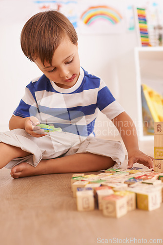 Image of Boy, child and building blocks for toys, playing and learning with development and growth at home in playroom. Fun, activity and playful with wood bricks, young toddler kid and educational games