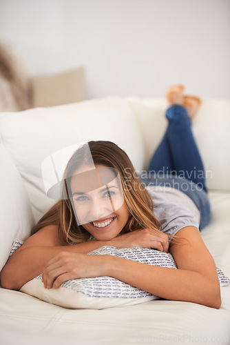 Image of Woman, portrait and relax on sofa in living room, calm and comfort with positive mood for leisure. Rest, lying down with pillow and smile for stress relief, break on day off or weekend at home