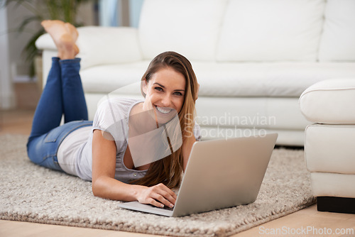 Image of Woman, portrait and laptop on floor with internet for typing, communication and email on mat in living room of home. Person, smile or technology on ground with relax, streaming show or watching video