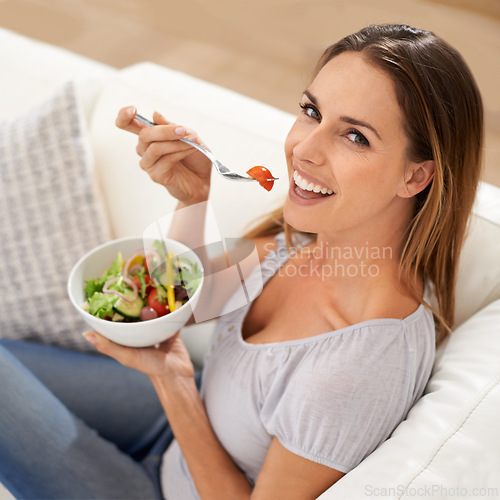 Image of Portrait, happy woman and eating salad on sofa for lunch and healthy food for nutrition in home. Smile, face and young lady with vegetables in above, vitamins and detox on weekend in modern apartment