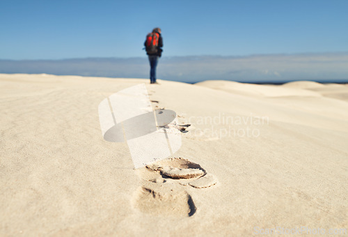 Image of Person, hiking and walking on sand dunes for fitness adventure in desert and extreme sport in arid climate. Athlete, back or survival gear for nature exploration, footprints or wanderlust vacation