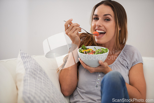 Image of Portrait, happy woman and eating a salad on couch, lunch and healthy food for nutrition in home. Smile, face and young lady with vegetables on sofa, vitamins and detox or weight loss in living room