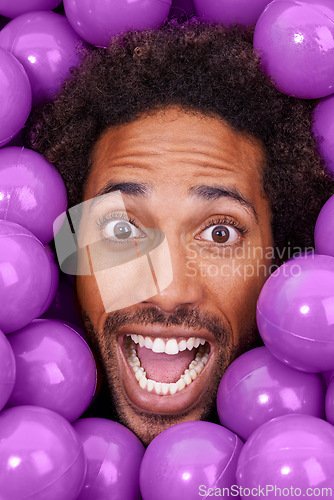 Image of Ball pit, excited and portrait of black man with plastic toys for fun, playful and happy on background. Surprise, facial expression and face of person with purple balls, decoration and objects