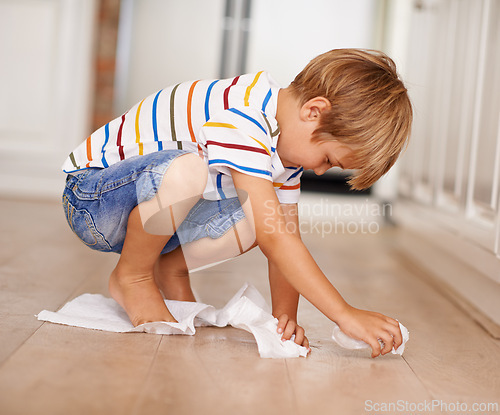 Image of Kid, cleaning and floor at home for mess, spill or household chores for childhood development. Boy, toilet paper and responsibility in house with hygiene, maintenance and learning responsibility