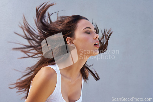 Image of Woman, hair or shake as hairdressing, hairstyle or promo of healthy, texture or growth for scalp. Wind, long or natural style as grooming in maintenance, shine or volume in studio on grey background