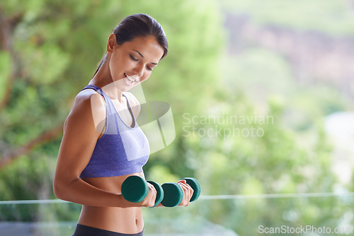 Image of Happy woman, fitness and weightlifting with dumbbells for exercise, workout or muscle gain on balcony. Female person with smile for lifting weight or small barbells for outdoor training on terrace