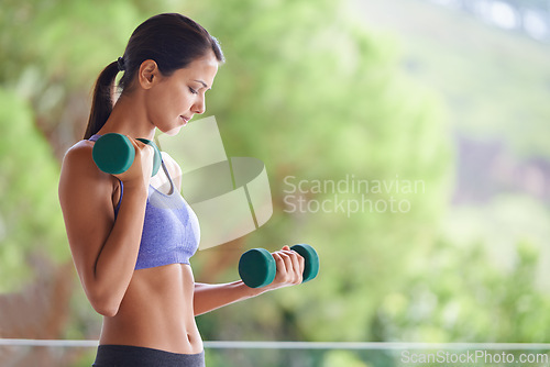 Image of Woman, weightlifting and exercise with dumbbells for muscle gain, workout or outdoor training on balcony. Young female person with small barbells for sport, fitness or health and wellness in nature