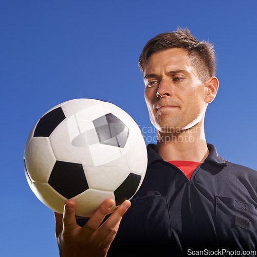 Image of Face, soccer and ball with man on blue sky background as referee for competition, game or match. Fitness, football and sports with serious person outdoor for beginning or start of tournament