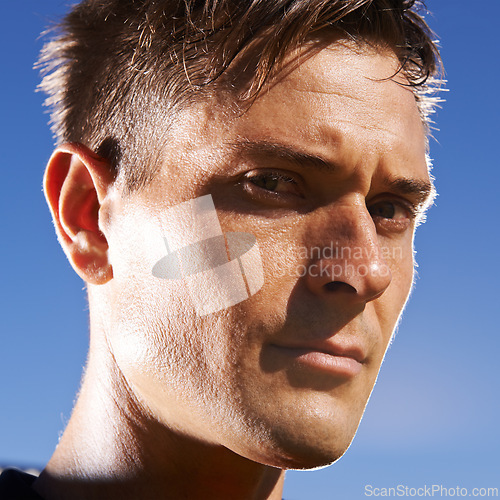 Image of Man, portrait and confident soccer player in outdoors, athlete and competitive for match or game. Male person, serious face and determined for competition, blue sky and focus for football challenge