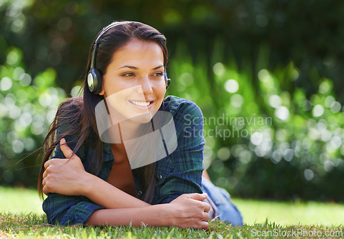 Image of Grass, thinking and woman with headphones, listening to music and streaming audio with peace, relaxing and sunshine. Person in a park, outdoor and girl with headset and podcast with radio and sound