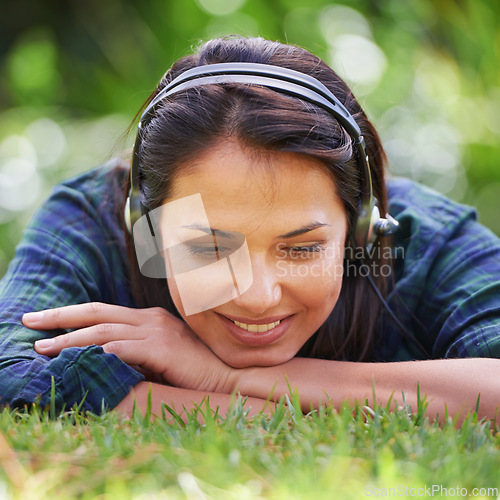 Image of Park, grass and woman with headphones, listening to music and streaming podcast with peace, relax and sunshine. Person in a backyard, outdoor or girl with headset or audio with radio, summer or sound